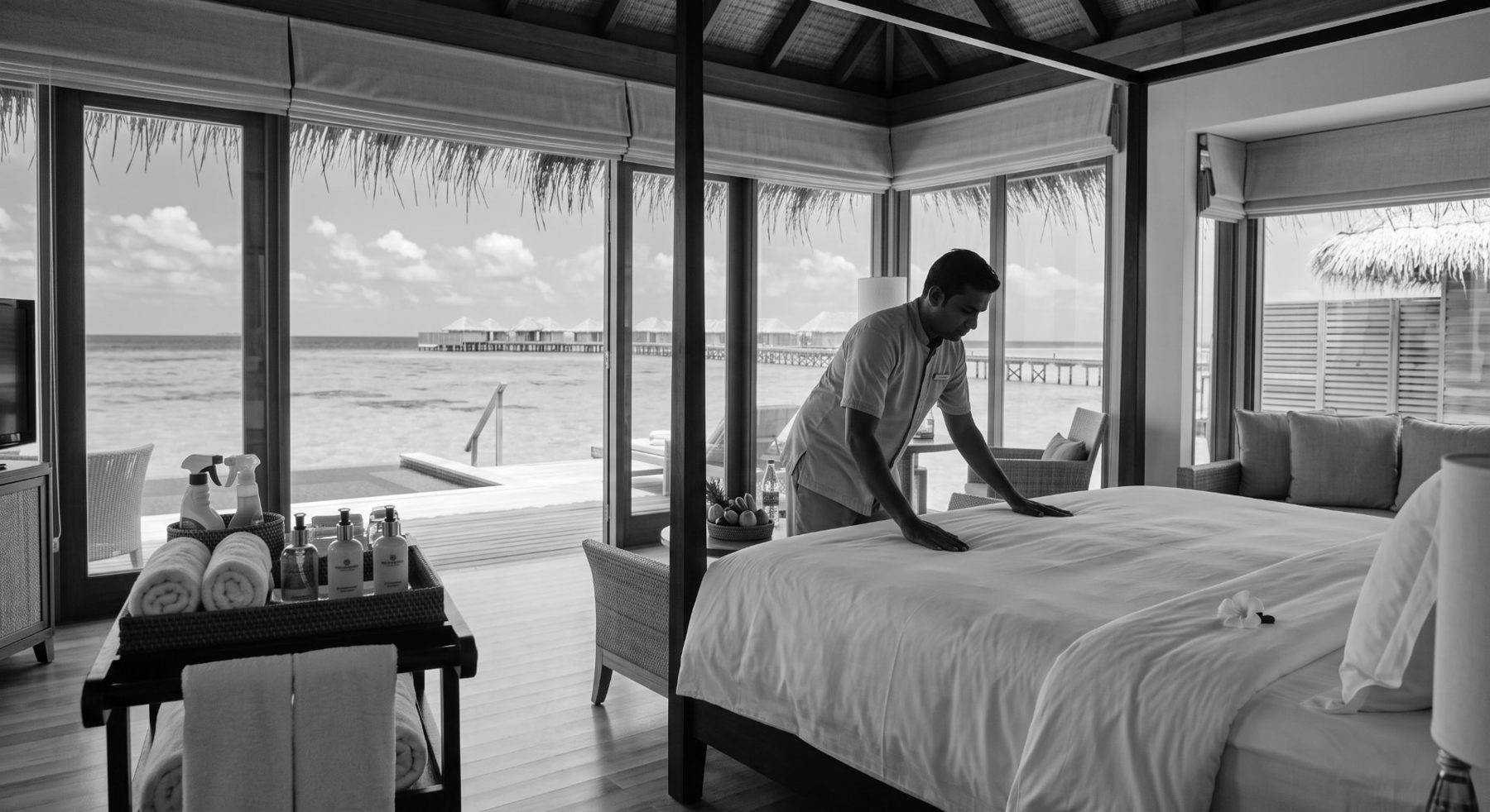 Housekeeping attendant preparing the bed in a Maldives overwater villa
